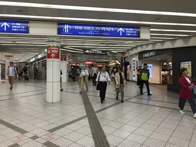 頭上にヒルトンプラザイースト、エストの青い看板が見えます。そのまままっすぐお進みください。